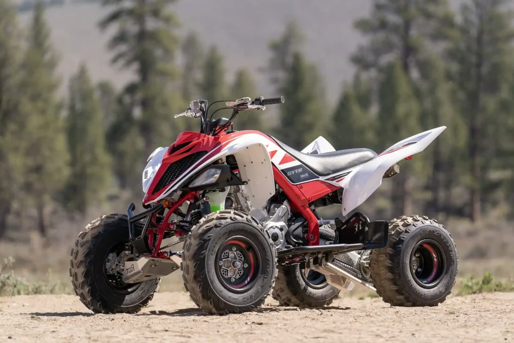 موتور چهارچرخ قرمز و سفید یاماها در مسیر خاکی با پس‌زمینه جنگل